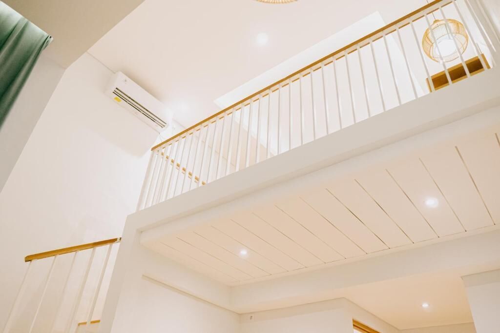 A multi-level interior with white walls, a wooden railing, and recessed lighting.