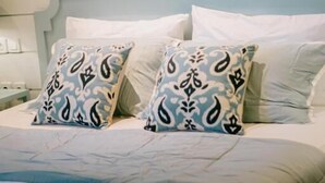A bedroom with a bed, pillows, and a wall-mounted decorative piece. - Casa Amarta Canggu - Boutique Loft & Detox Spa (Canggu)