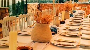 A dining table set with plates, cutlery, and a vase with dried plants. - Al-jabal castle Hotel - Ajloun (Ajloun)