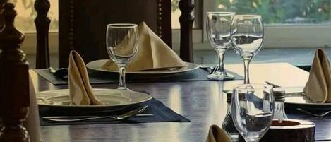Mesa lista para comer, con platos, servilletas y copas de vino.