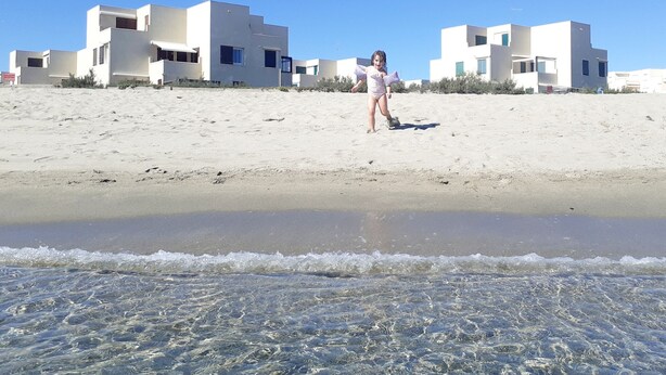 Une plage avec, en arrière-plan, des bâtiments blancs aux lignes modernes.
