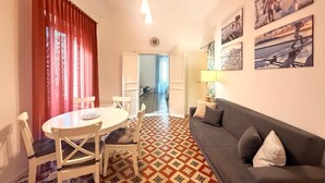 Un salon comprenant un canapé, une table à manger avec des chaises, un sol à motifs et des œuvres d’art accrochées aux murs.