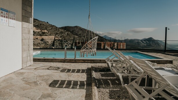 A pool area with a view of mountains, a hanging chair, and lounge chairs. - Villa Dubrovnik Heights – Private pool and jacuzzi with sea view (Ivanica)