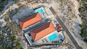 Vue aérienne d’une propriété comprenant deux bâtiments, une piscine et un espace de stationnement.