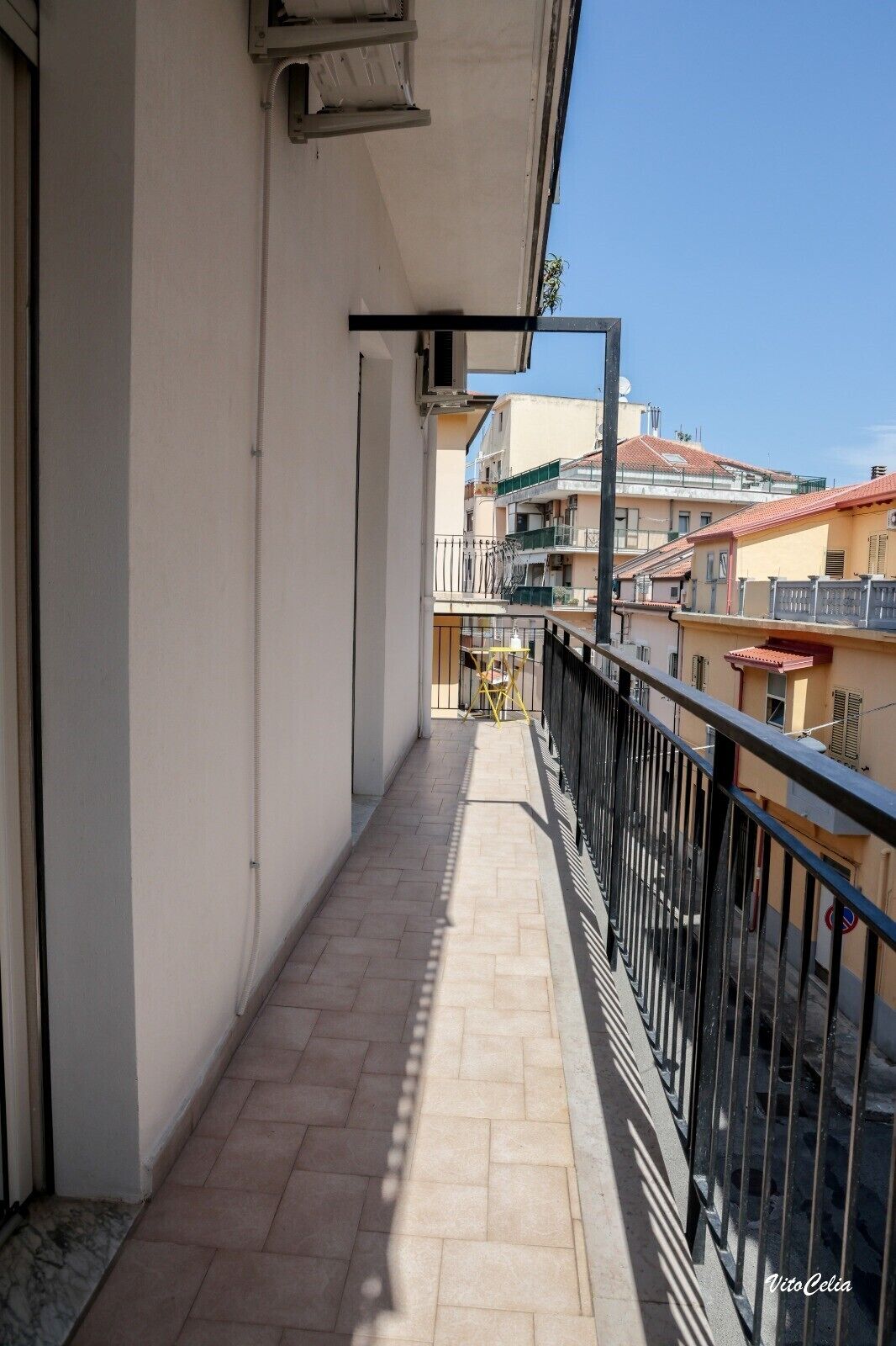 A narrow balcony with a tiled floor, a metal railing, and a view of adjacent buildings.