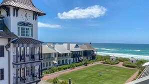 A coastal hotel with a clock tower, multiple balconies, and a view of the ocean. - Toes in the Water (Rosemary Beach)