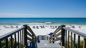 A wooden staircase leading to a beach with umbrellas and beach chairs. - Toes in the Water (Rosemary Beach)
