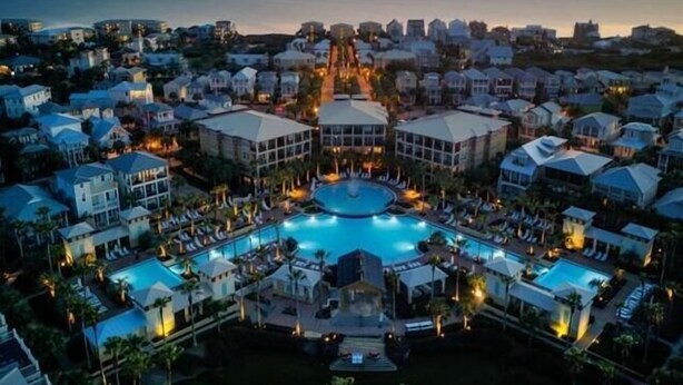 A resort with a central pool, multiple buildings, and a view of the sea at sunset. - Toes in the Water (Rosemary Beach)