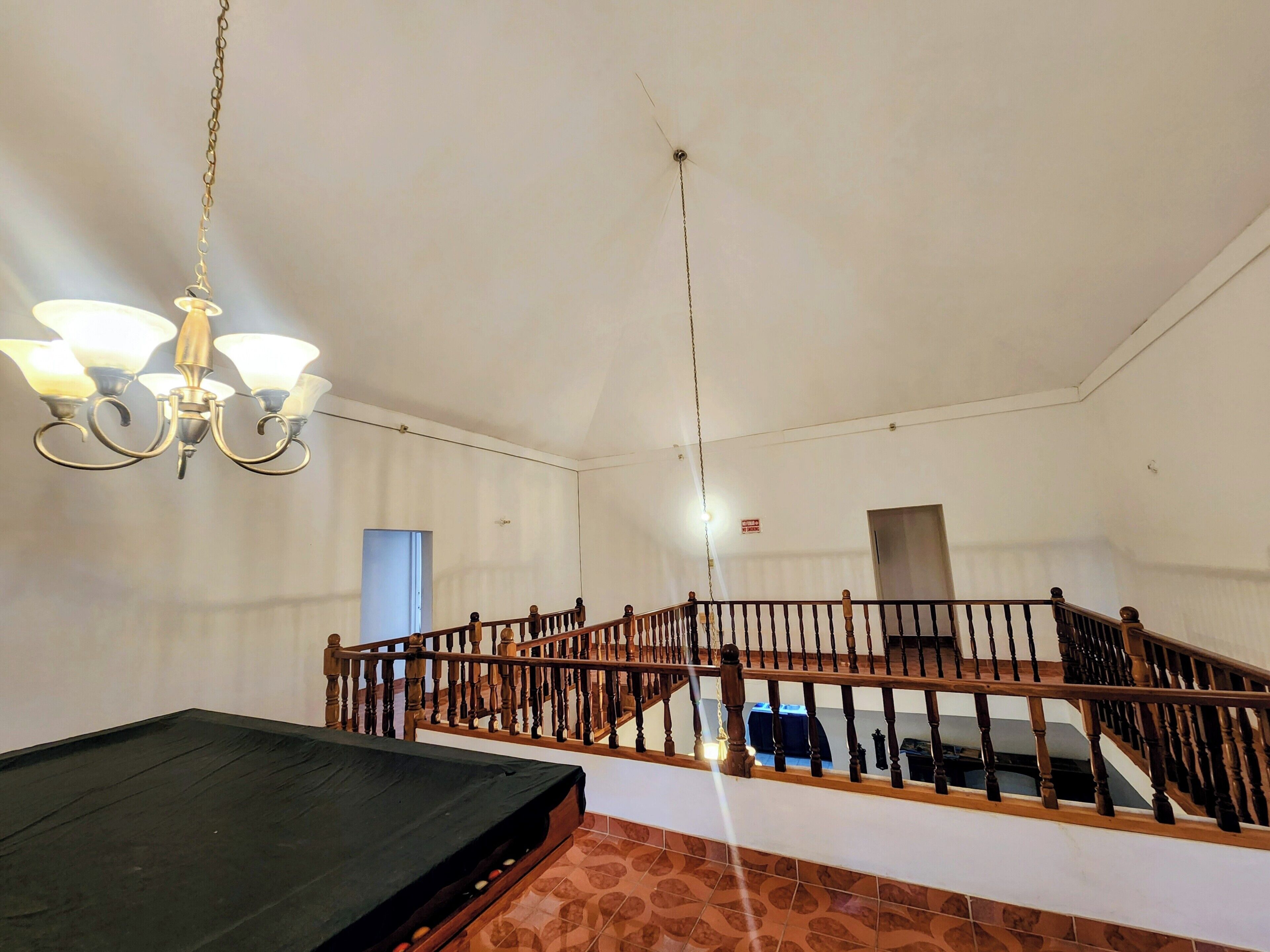 A room with a bed, a chandelier, a staircase, and a door.