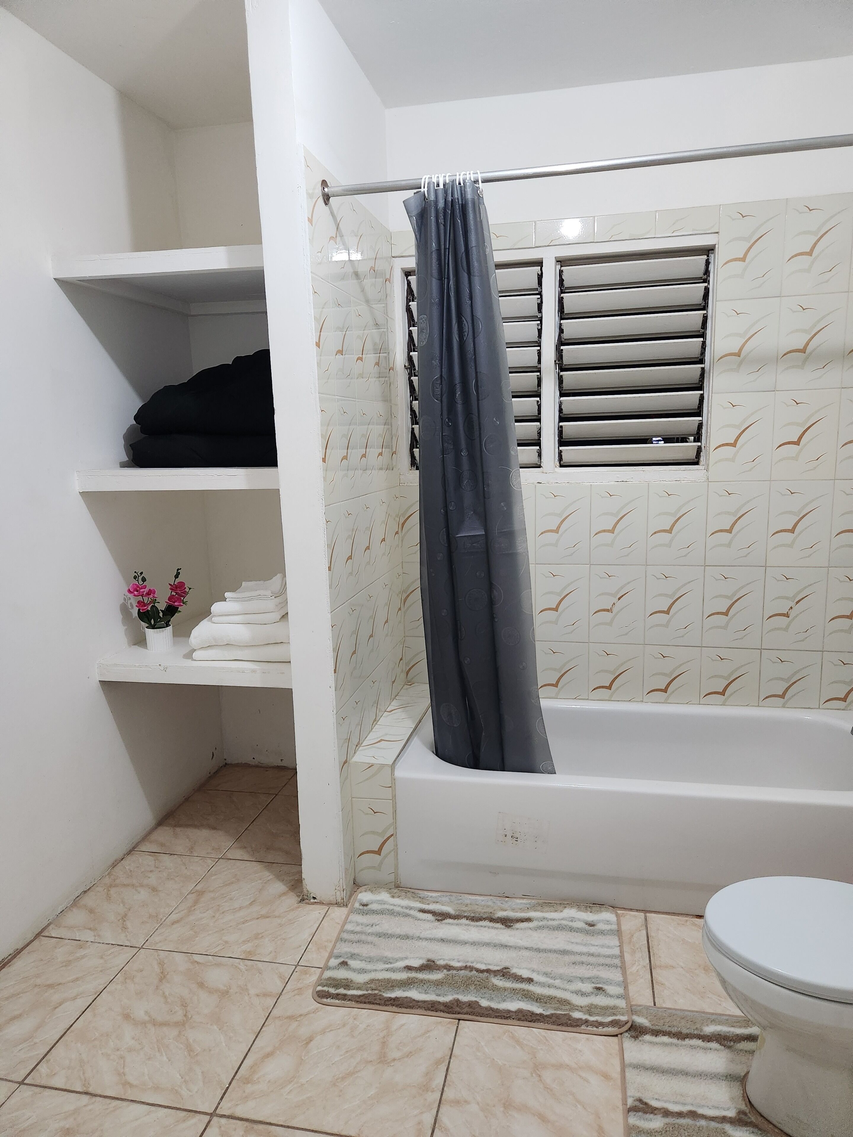 A bathroom with a bathtub, toilet, shower curtain, and tiled walls.