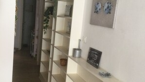 Käytävällä on seinään kiinnitetty hylly, kehystetty taulu ja ruukussa oleva kasvi.