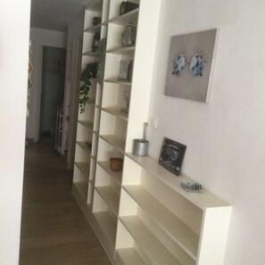 Cozy hallway with open shelving units and a door leading to another room.