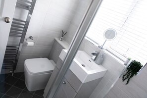 A modern bathroom with a toilet, sink, and glass shower enclosure. - 3 Bed House - Sleeps 6 - Garden - Parking - Wifi (Manchester)