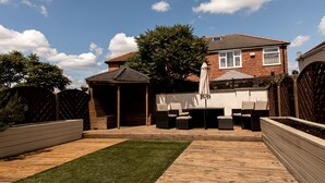 A backyard with a wooden deck, a small gazebo, and outdoor furniture. - 3 Bed House - Sleeps 6 - Garden - Parking - Wifi (Manchester)