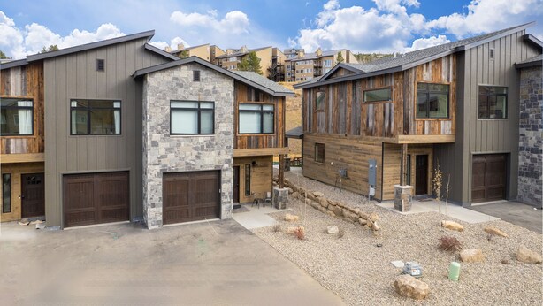 A row of modern multi-story buildings with stone and wood exteriors, large windows, and a clear sky. - Mountain townhouse w/ hiking, biking & adventure (Granby)