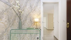 Ein Flur mit einem Glastisch, einem Blumenvasen und einer Lampe.