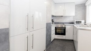 Eine moderne Küche mit weißen Schränken, einem eingebauten Backofen und einer Mikrowelle.