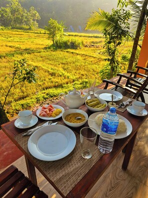 Una mesa preparada para el desayuno con vistas a un campo verde exuberante.