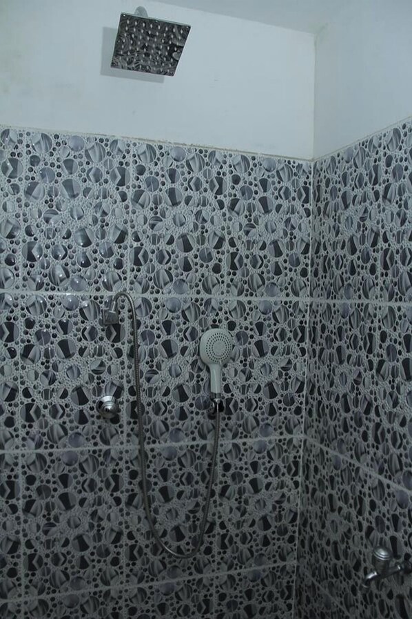 Un área de ducha con un revestimiento de azulejos estampados y un cabezal de ducha.