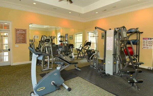 Ett gym med konditionsmaskiner, utrustning för styrketräning och speglar.