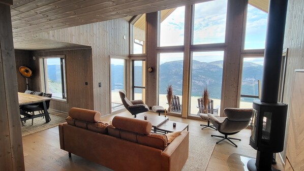 A spacious living area with a large window offering a mountain view, a cozy sofa, a dining table, and a fireplace.