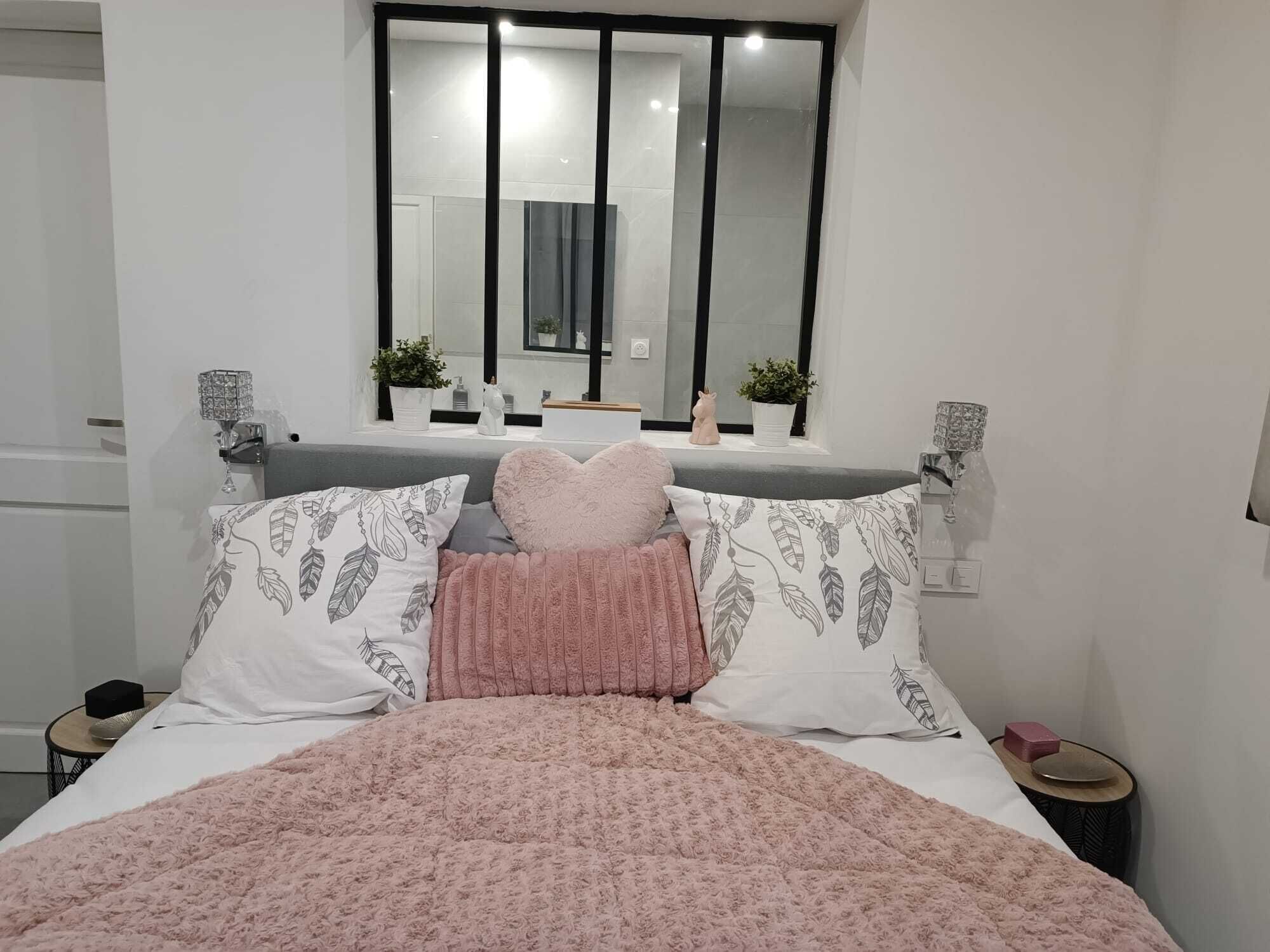 Un dormitorio moderno con una cama grande, un espejo sobre la cama y dos mesitas de noche.