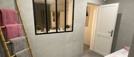 A bathroom with a mirror, a sink, and a towel rack.