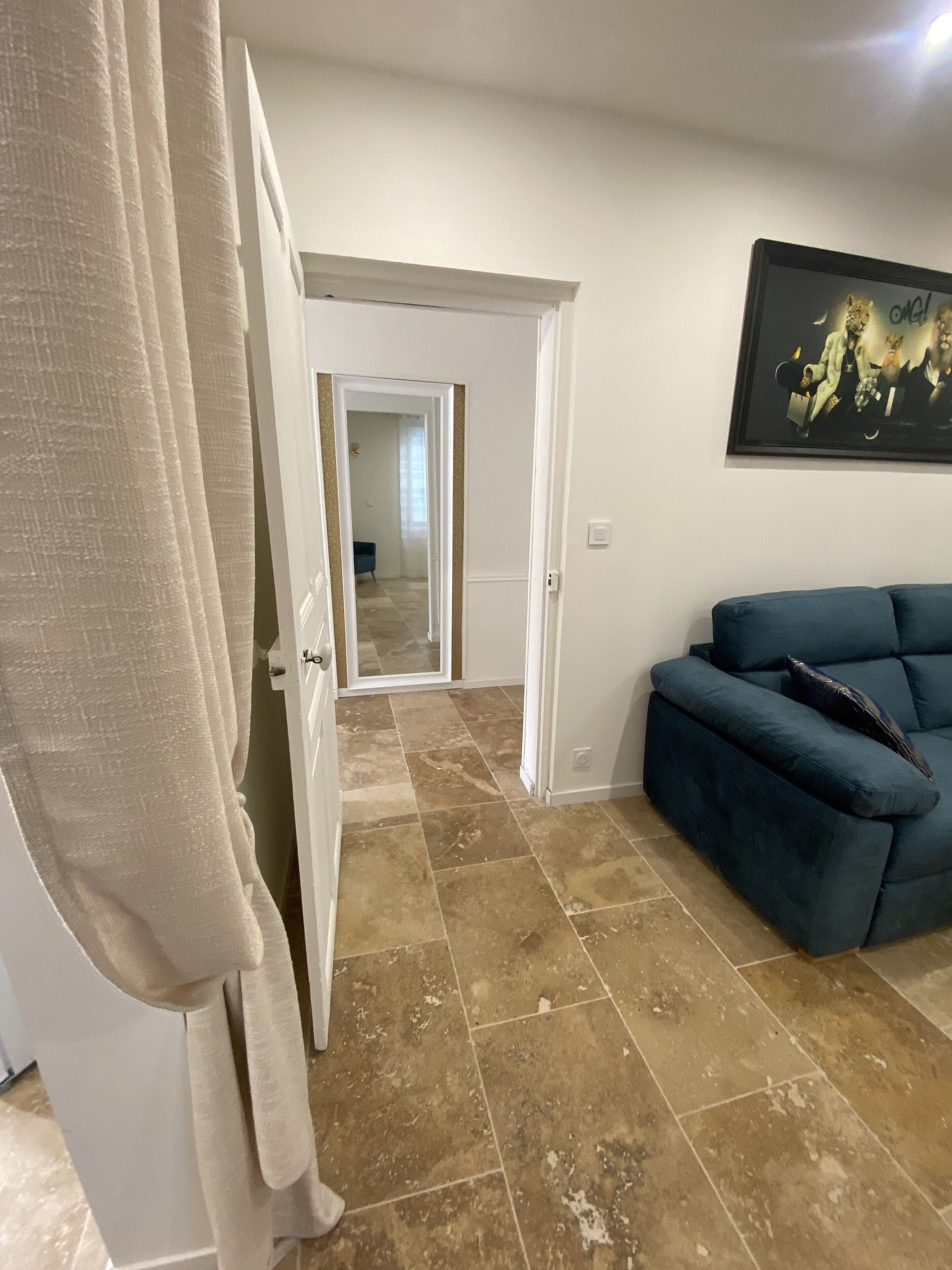 A living room with a blue sofa, a door leading to another room, and a tiled floor.
