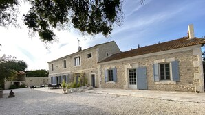 A stone building with a tiled roof, outdoor seating, and a gravel courtyard.