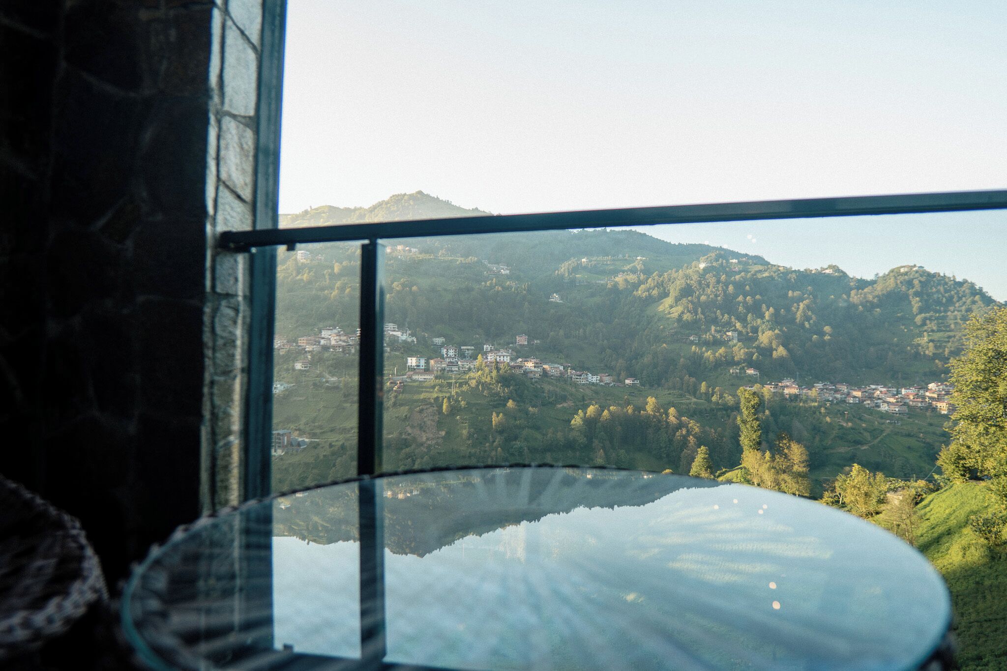 A view from a window overlooking a valley with buildings and hills.