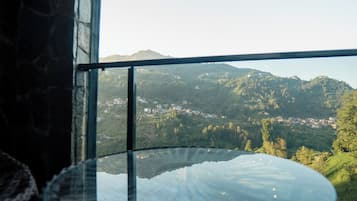 A view from a window overlooking a valley with buildings and hills.