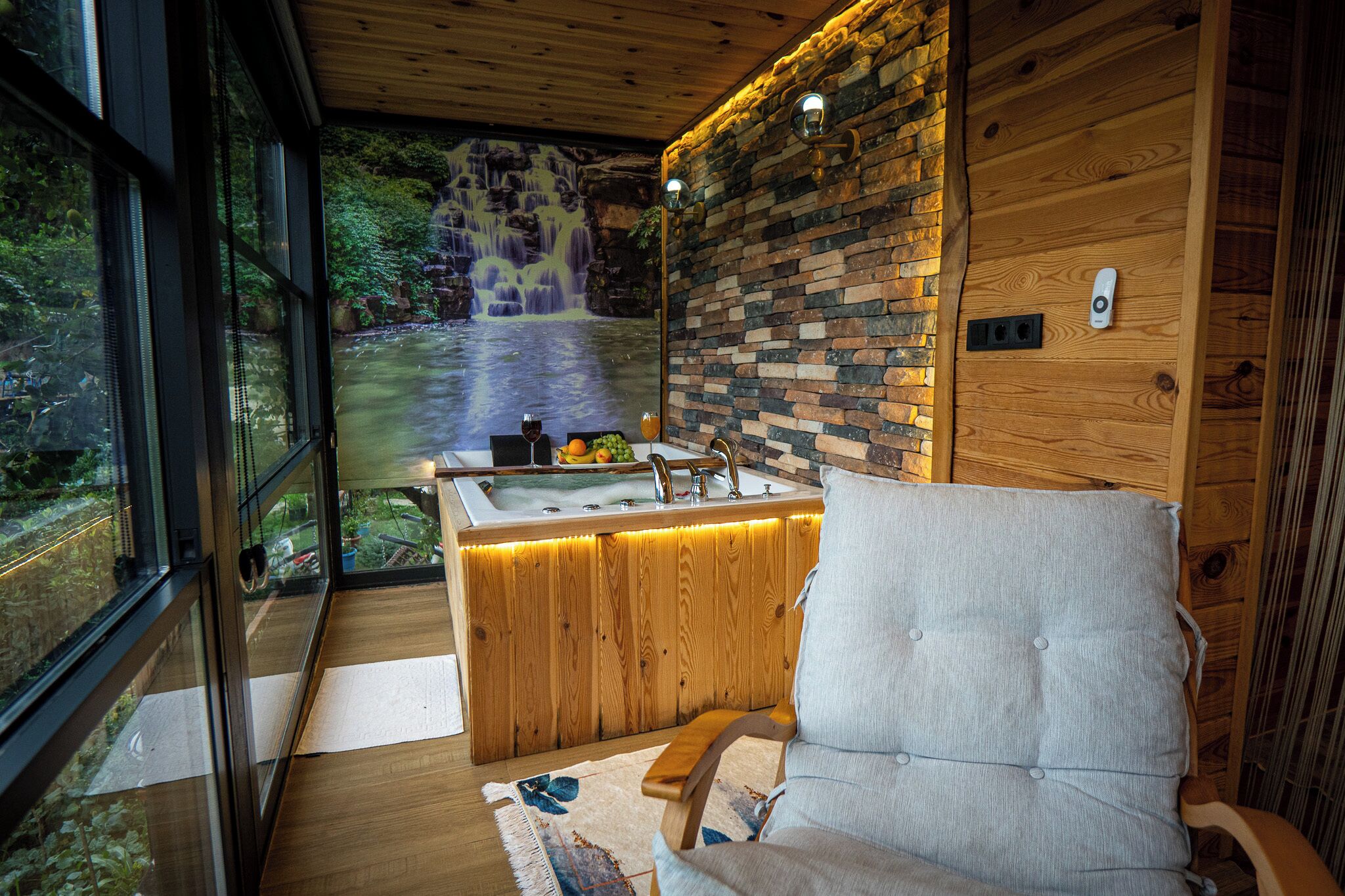 A bathroom with a wooden vanity, a large window, and a view of a waterfall.