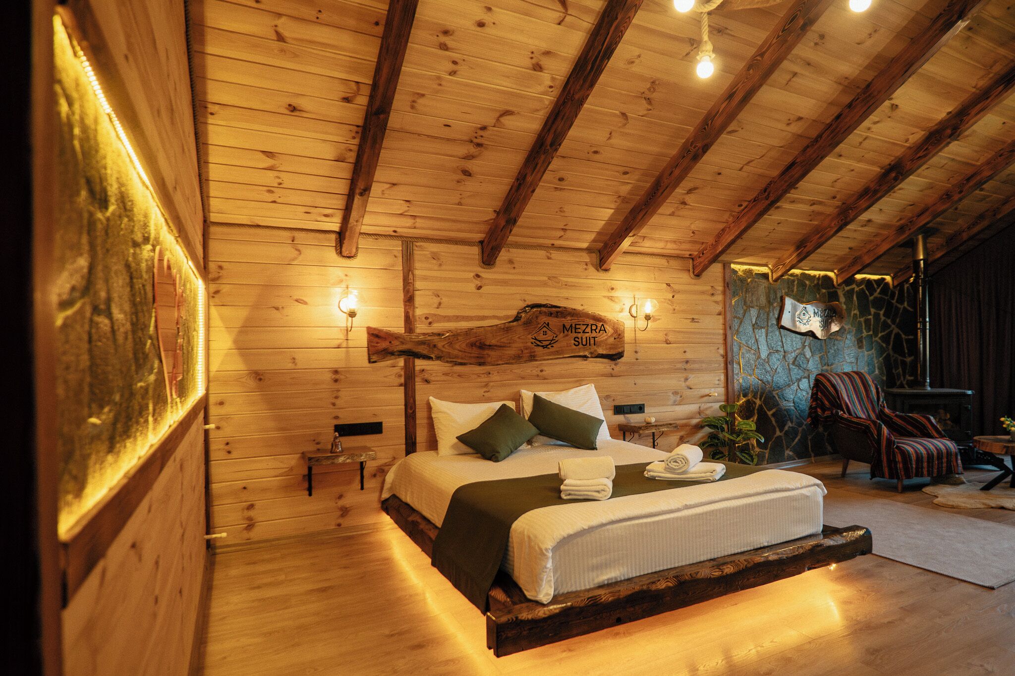 Ein Schlafzimmer in einer Holzhütte mit einem Bett, Kissen, einem Nachttisch und einer Steinwand.