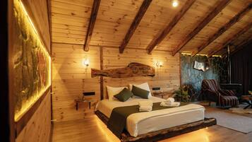 Ein Schlafzimmer in einer Holzhütte mit einem Bett, Kissen, einem Nachttisch und einer Steinwand.