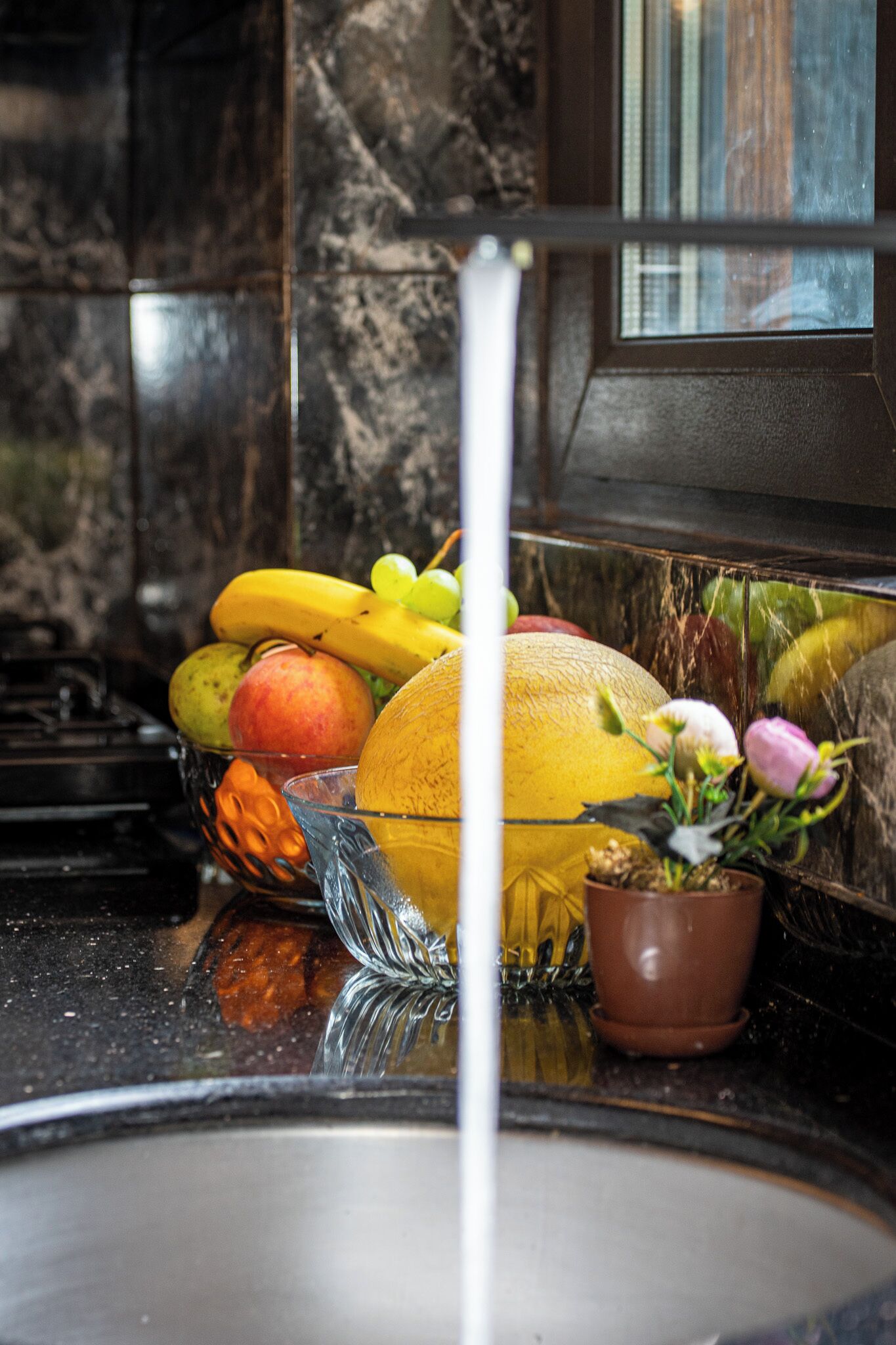 A kitchen counter with fruits and a potted plant.