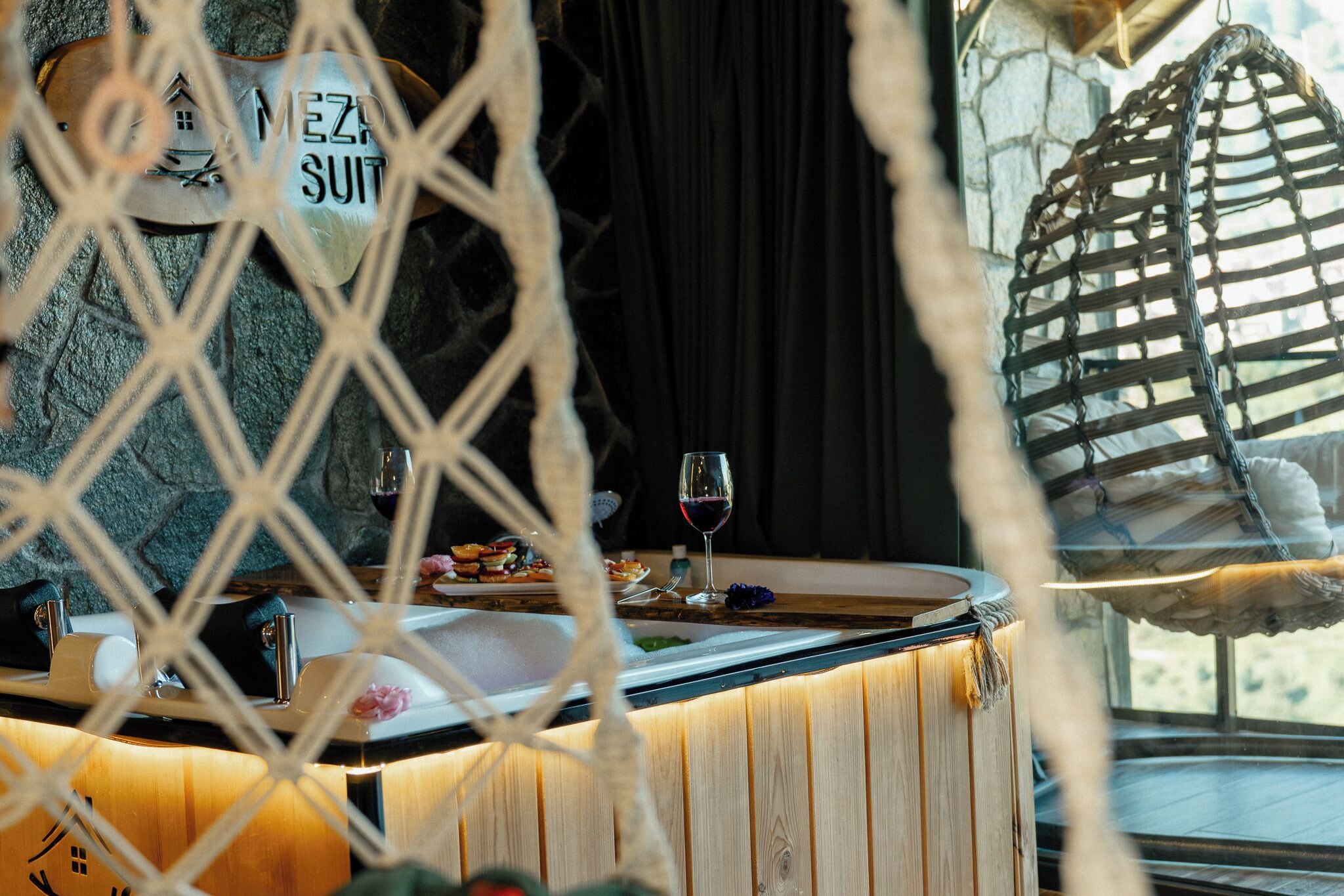A cozy interior with a wooden counter, a wine glass, and a hammock.