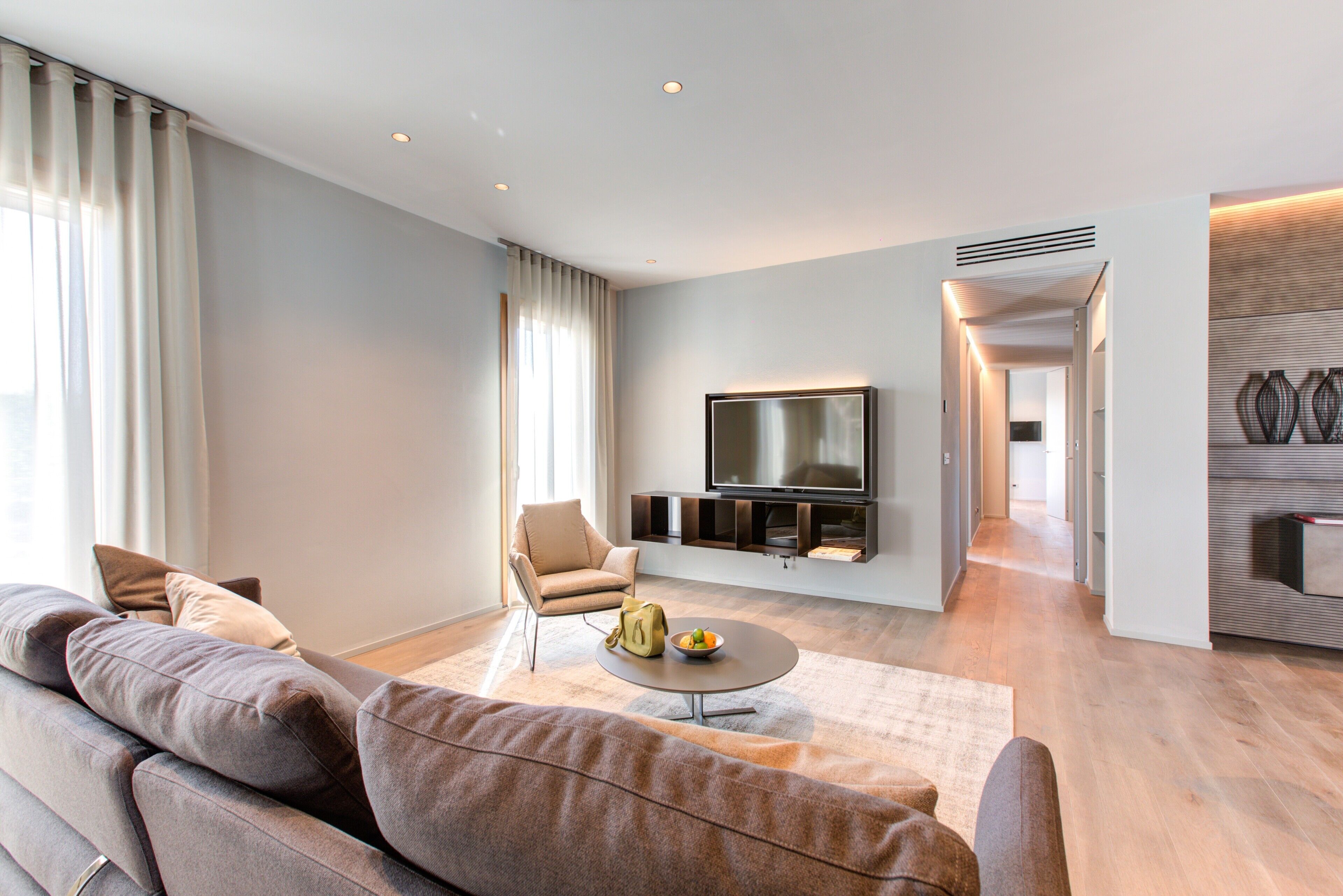 A modern living room with a sofa, a coffee table, and a TV mounted on the wall.