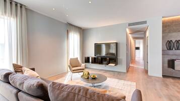 A modern living room with a sofa, a coffee table, and a TV mounted on the wall.