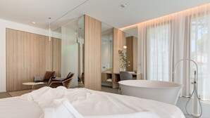 A modern hotel room with a large bed, a desk, a chair, and a bathtub. - Villa Italia (Cesenatico)