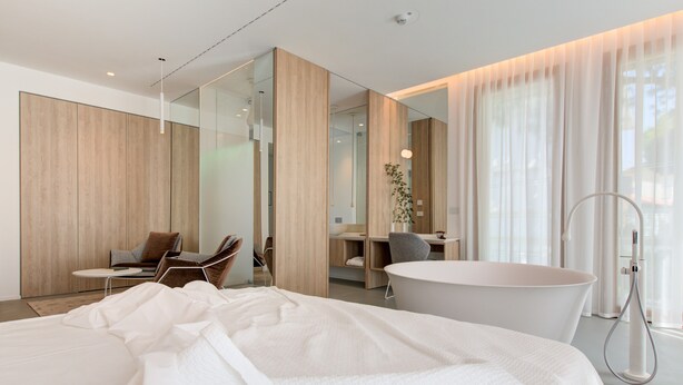 Una habitación de hotel moderna con una cama grande, un escritorio, una silla y una bañera.
