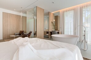 A modern hotel room with a large bed, a desk, a chair, and a bathtub. - Villa Italia (Cesenatico)