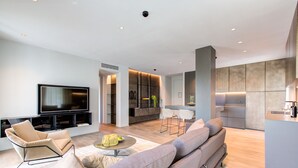 Una sala de estar moderna con una televisión de pantalla plana, un sofá, una mesa de centro y un comedor con sillas.
