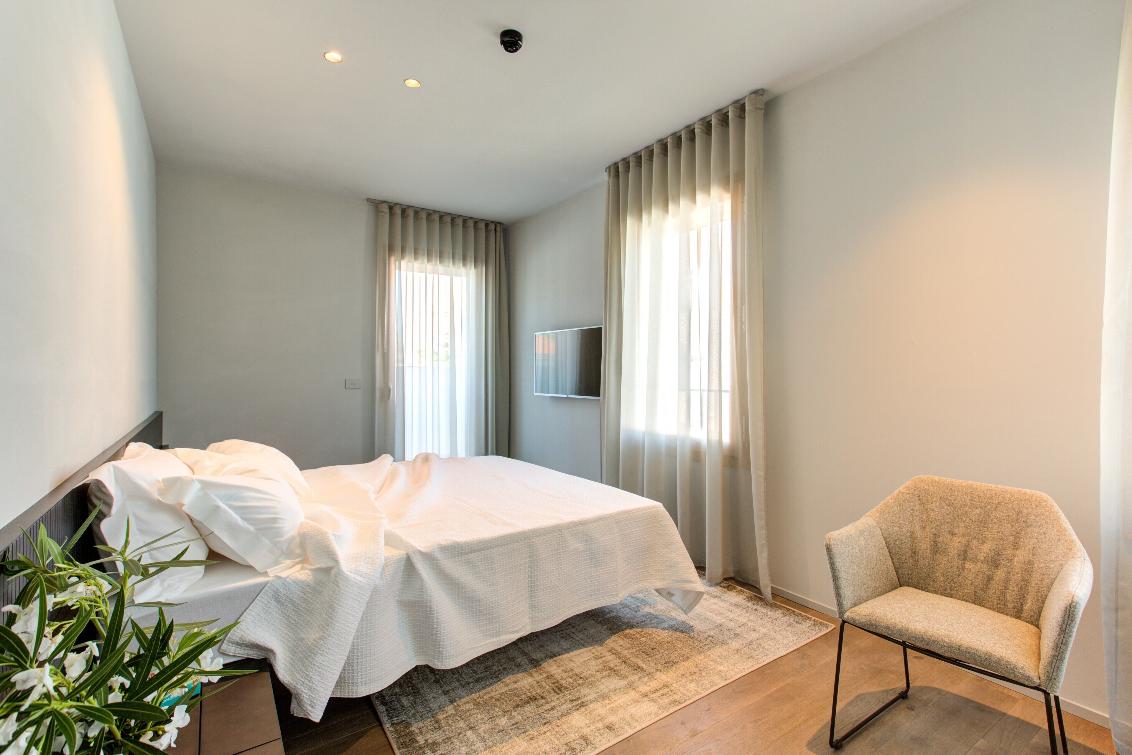 Une chambre à coucher avec un lit, une chaise, un téléviseur et une plante.