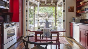 A kitchen with red cabinets, a wooden dining table, and a view of the outdoors.