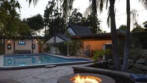 A swimming pool with a fire pit and lounge seating.