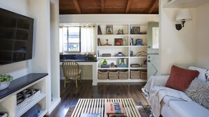 A living room with a sofa, a TV, a desk, and a bookshelf.