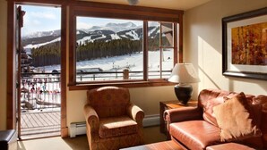 Un accogliente soggiorno con un'ampia finestra che si affaccia su un paesaggio montano innevato.