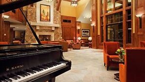 Un pianoforte a coda in un'ampia hall con pareti in pietra e dettagli in legno.