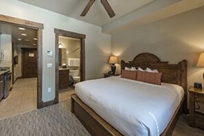 Relax in a spacious room with a large bed, flanked by a headboard and nightstand, and access to a hallway with a mirror and coat rack.