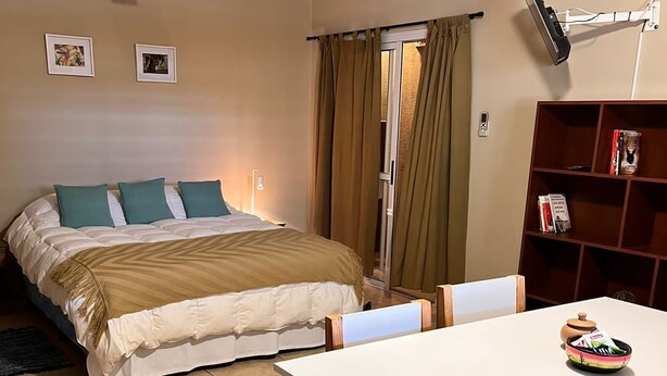 Een slaapkamer met een bed, nachtkastje, stoel, bureau, boekenplank en een airconditioning.